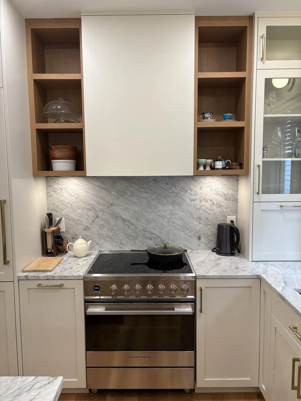 Custom cabinets with open oak shelving and a marble backsplash