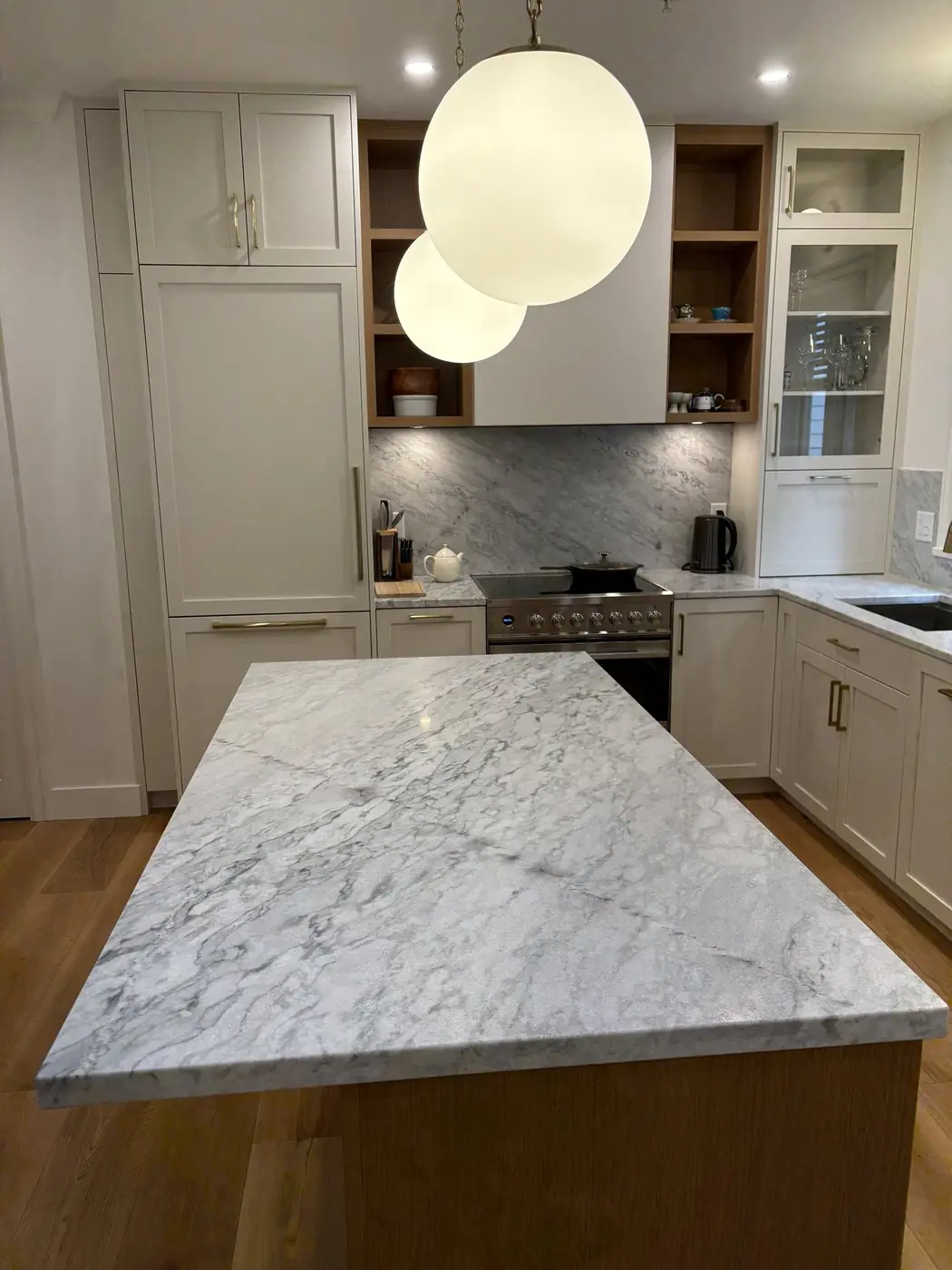 A marble-topped island under two globe pendants