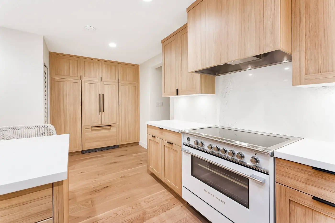 White-oak cabinet faces around a white range