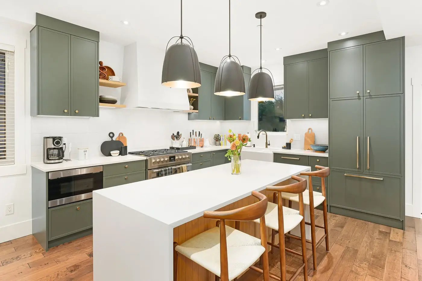 Finished kitchen with sage-green shaker cabinets, a white island and three pendant lights