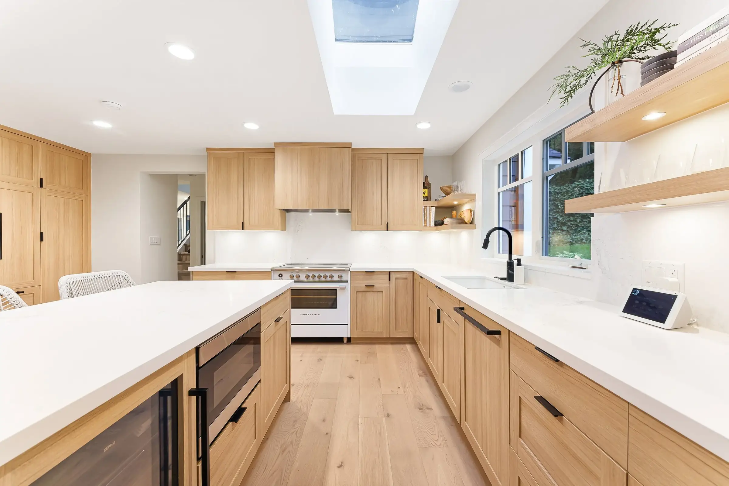 A finished white-oak kitchen under a skylight