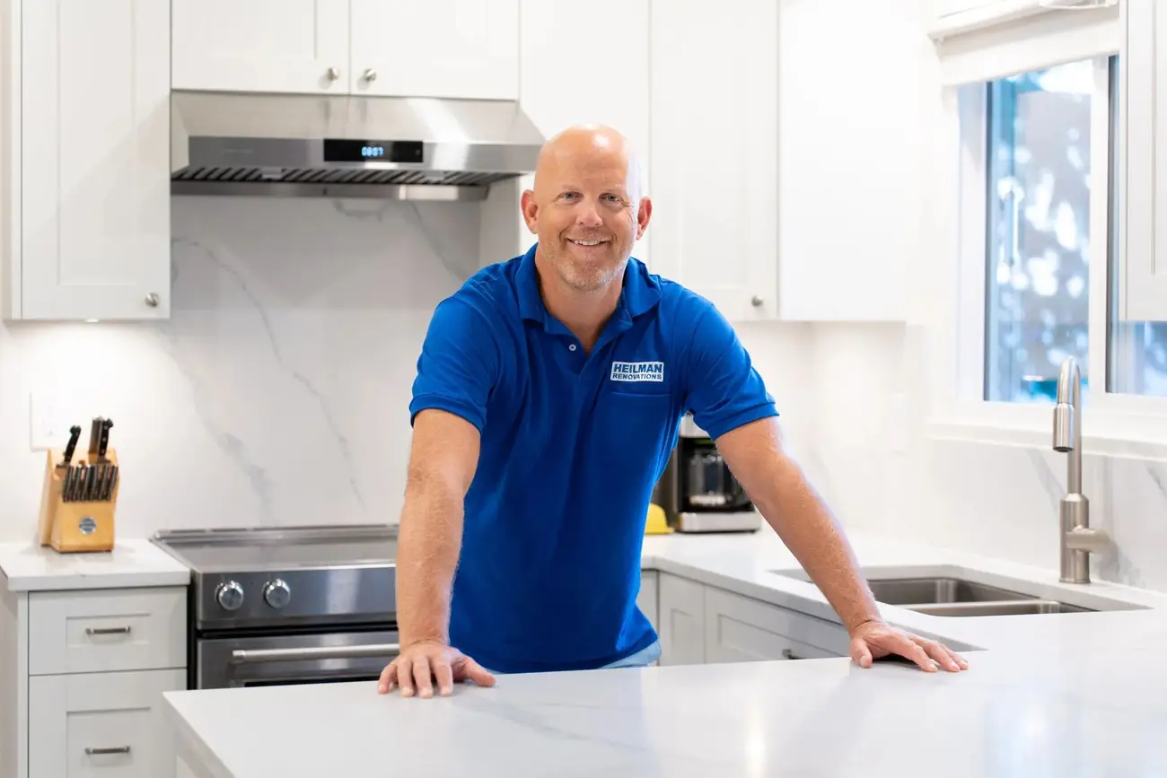 Joey Heilman in a blue Heilman Renovations shirt in a finished white kitchen