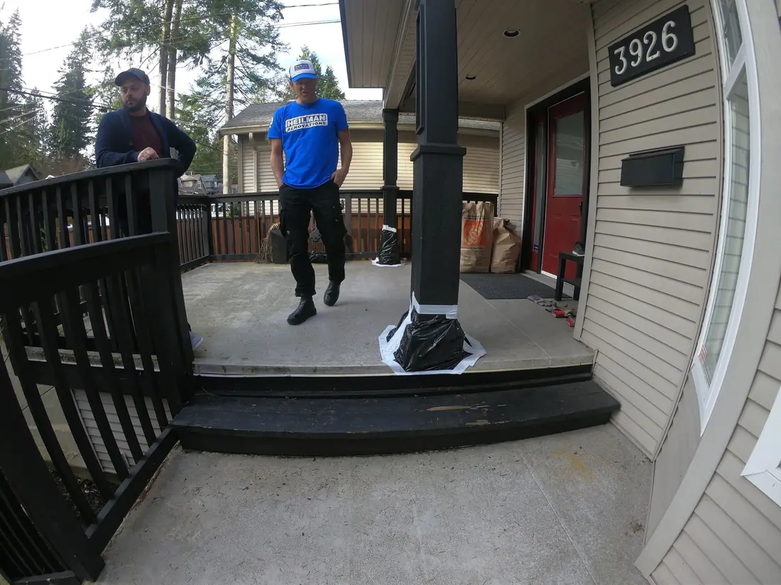 A Heilman crew member in a blue shirt on a homeowner's front porch